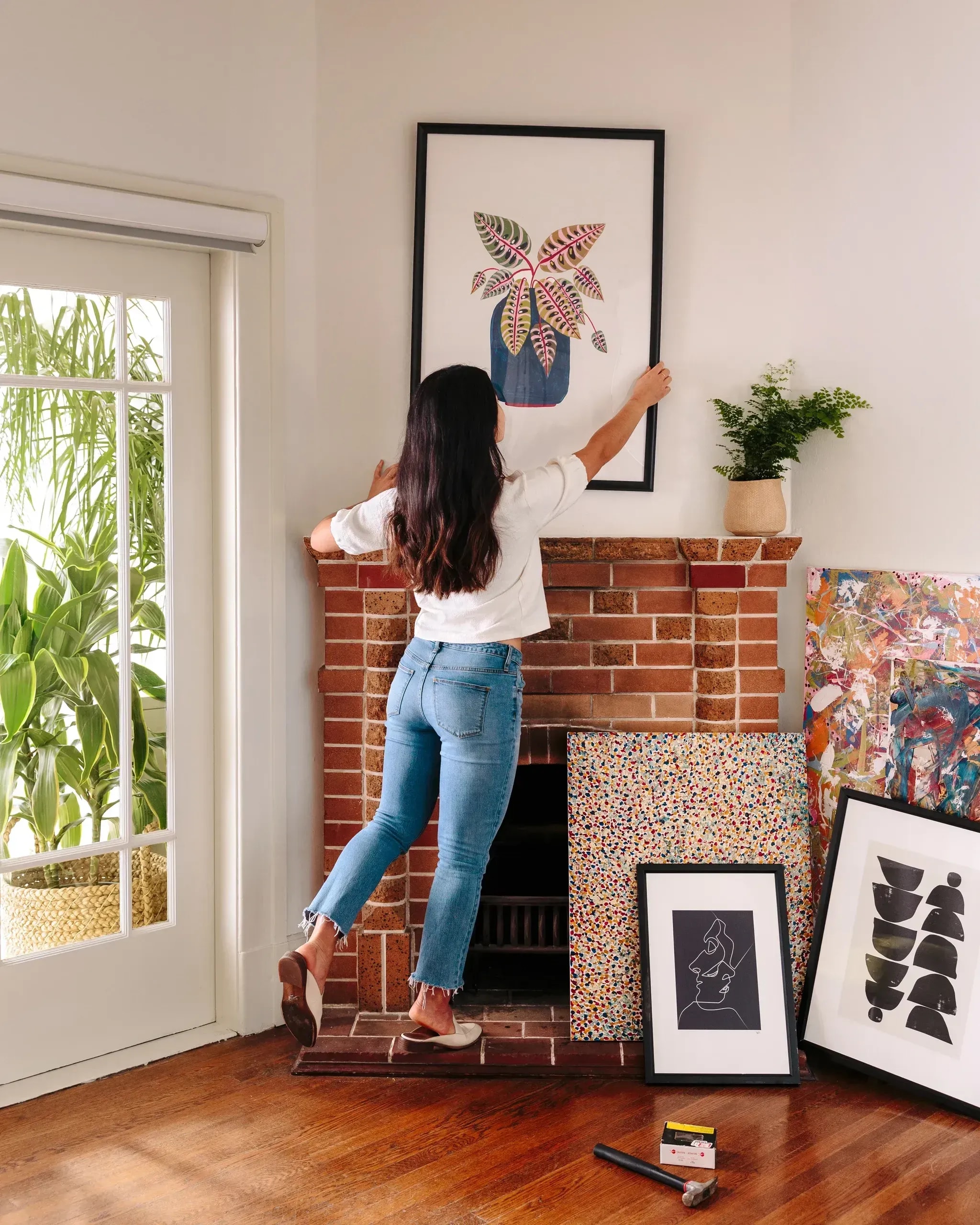 New homeowner setting up artwork after a move, with unpacked decor and tools—showcasing Marco’s post-move home services.